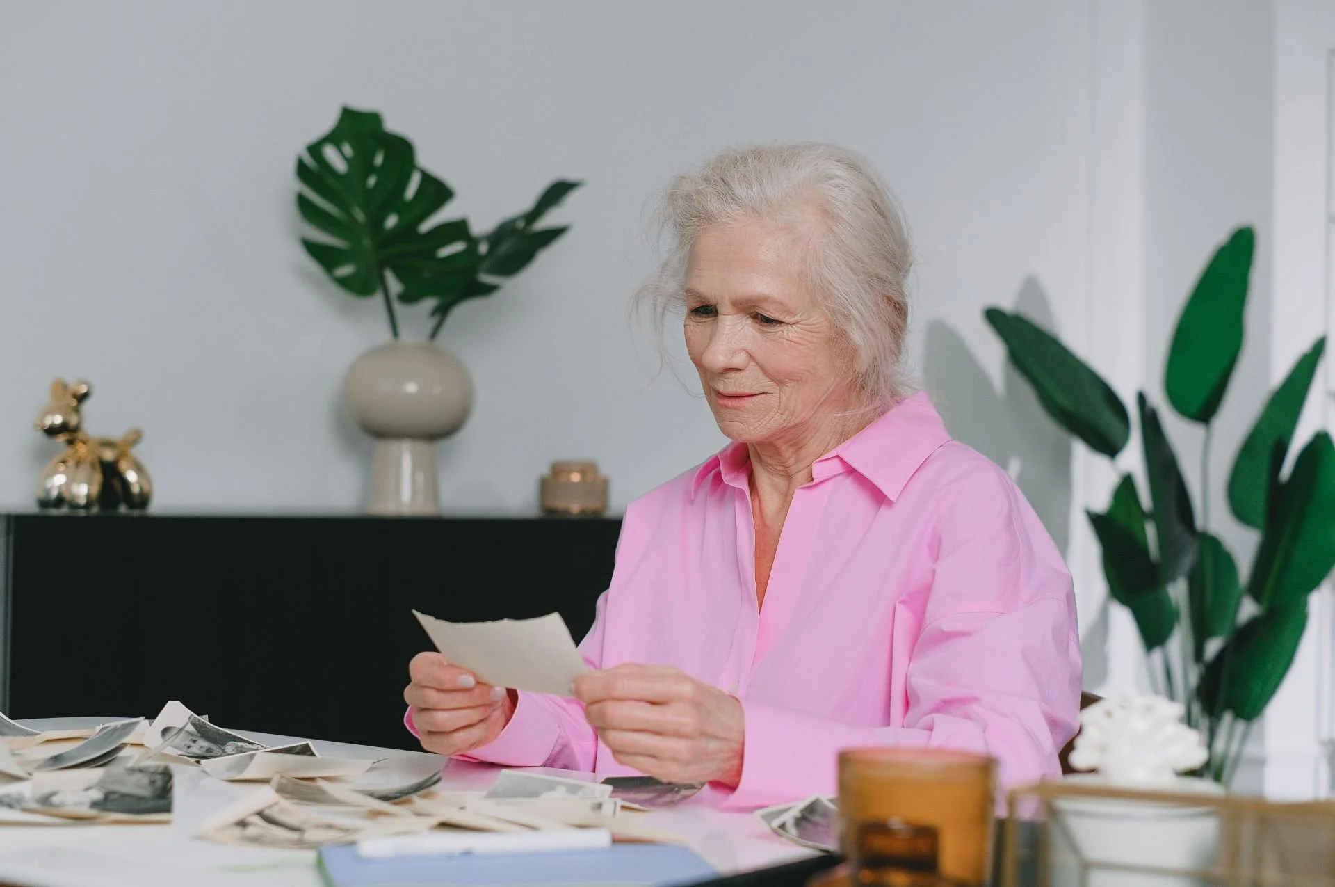Lady in pink looking at old photos. Downsizing can start small. Maybe just one drawer at a time.