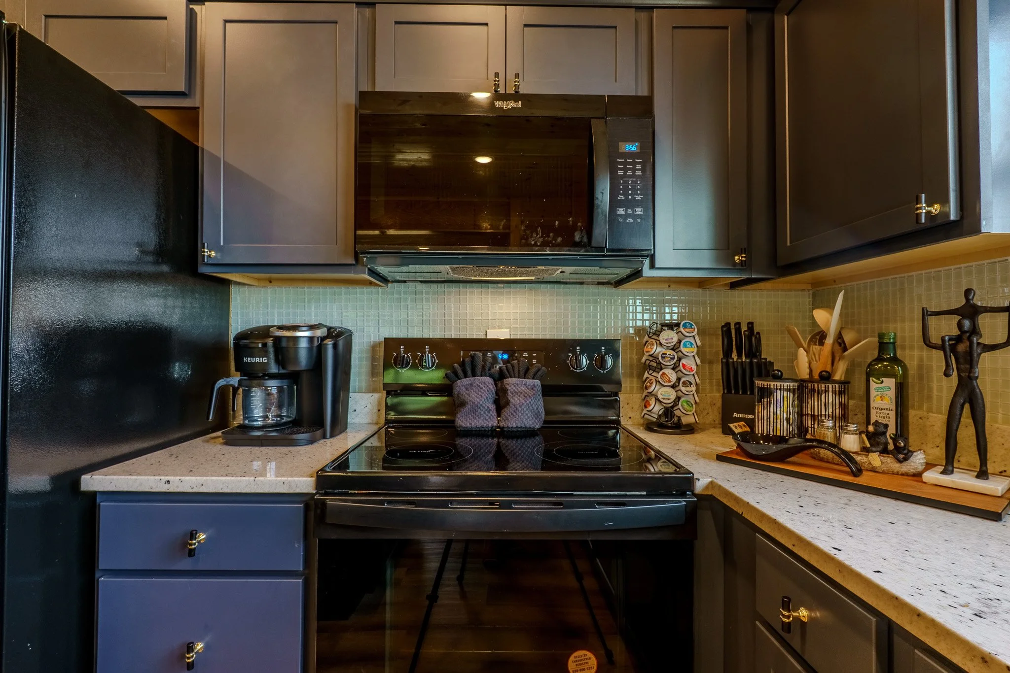 Kitchen counter with a coffee maker, electric stove, microwave, and various kitchen utensils and decorations.