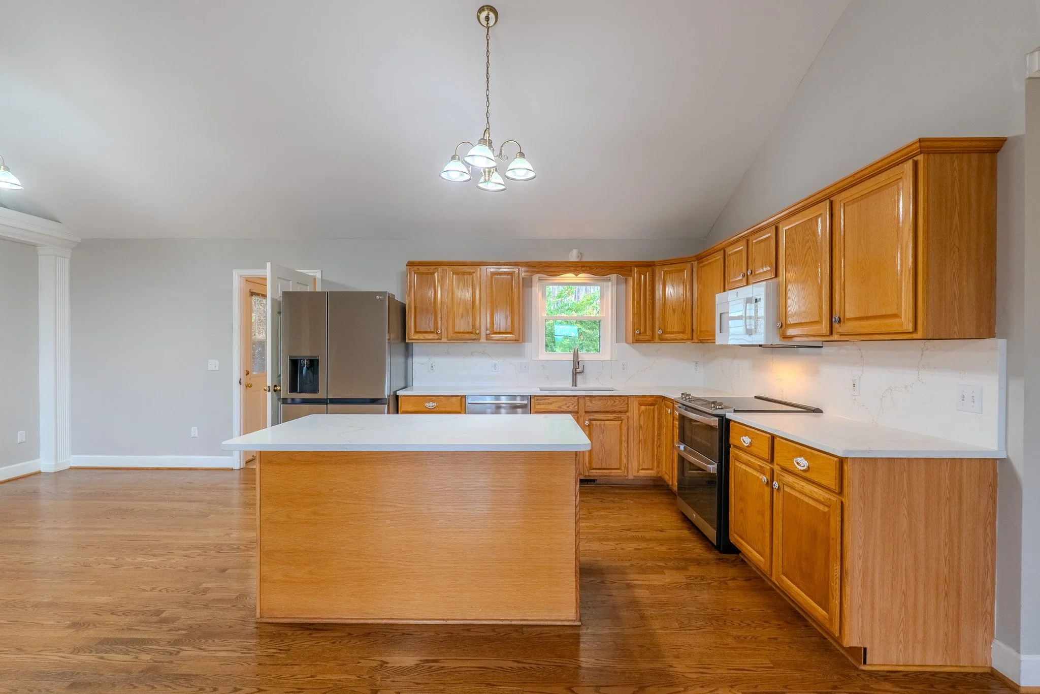 Kitchen with wooden cabinets, white countertops, a stainless steel refrigerator, and a small window above the sink.