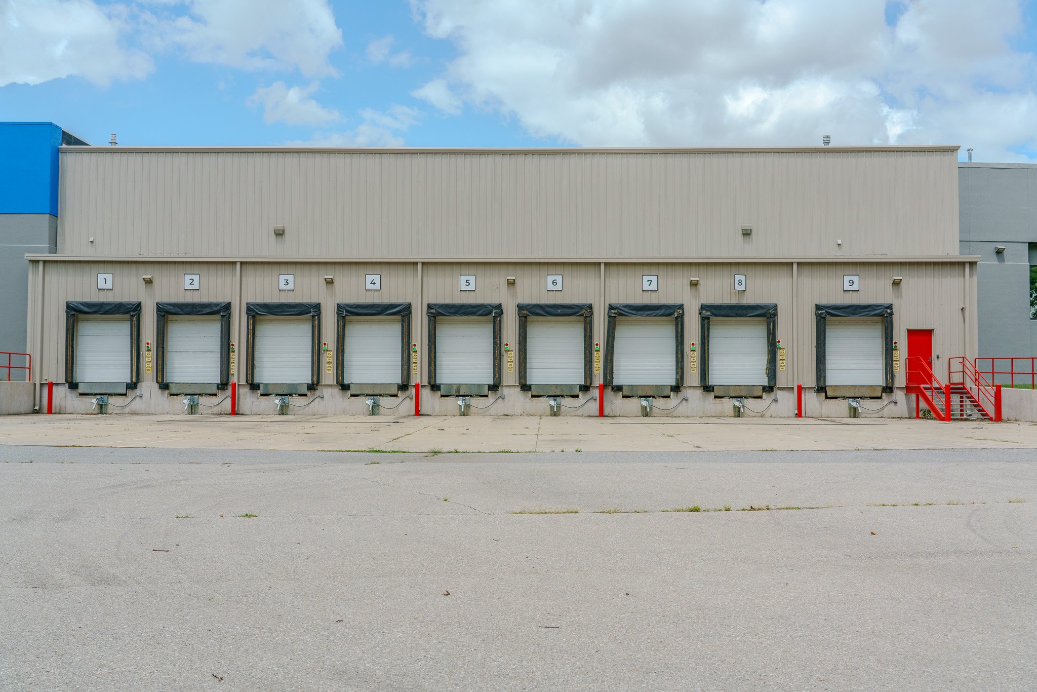 Warehouse building with nine loading docks, each numbered 1 through 9, and a red stairway on the right side.
