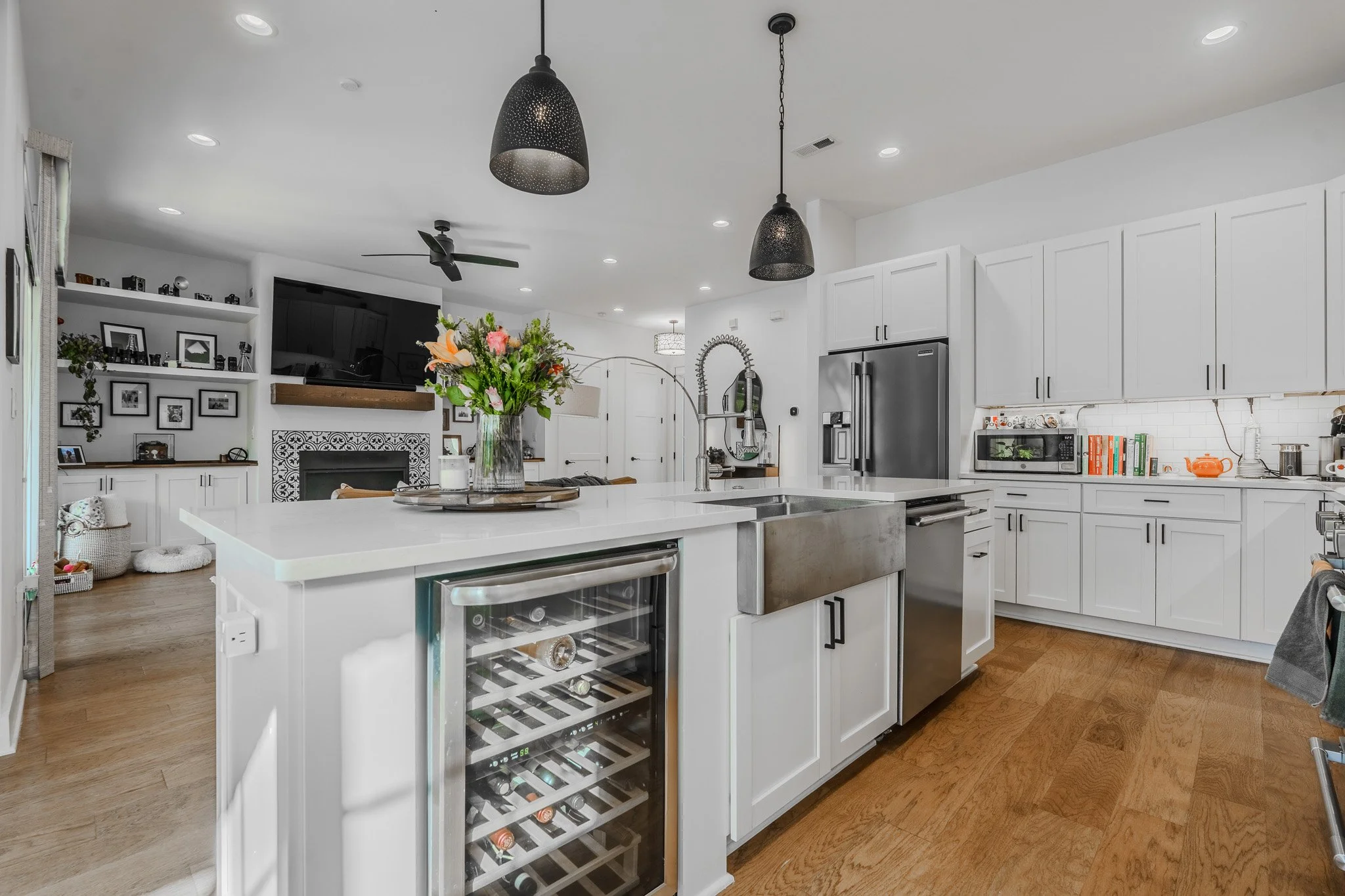 Modern kitchen with white cabinets, a large island with a sink, and black pendant lights, with a bouquet of flowers on the island.