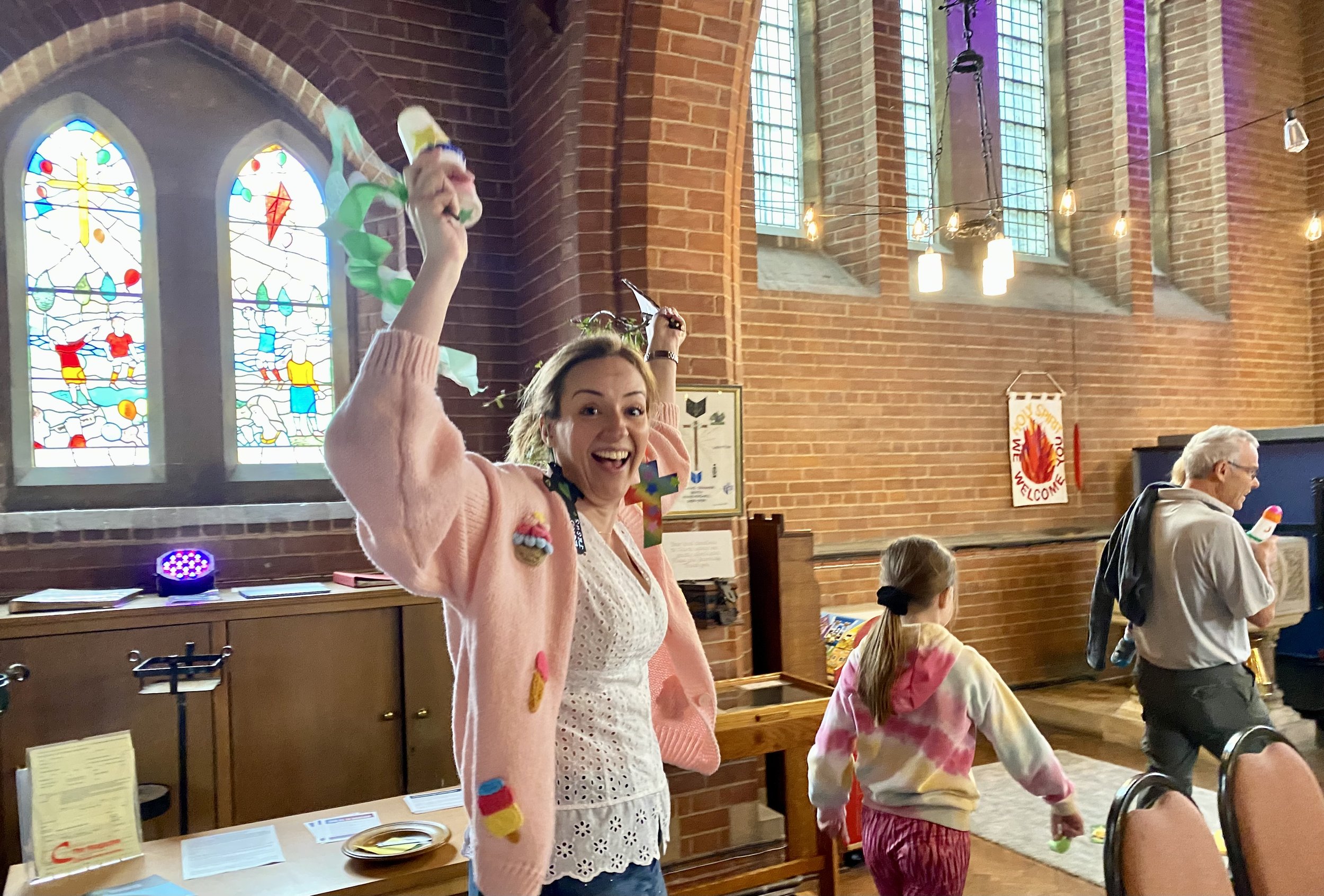 A woman smiling and celebrating inside a church with stained glass windows.