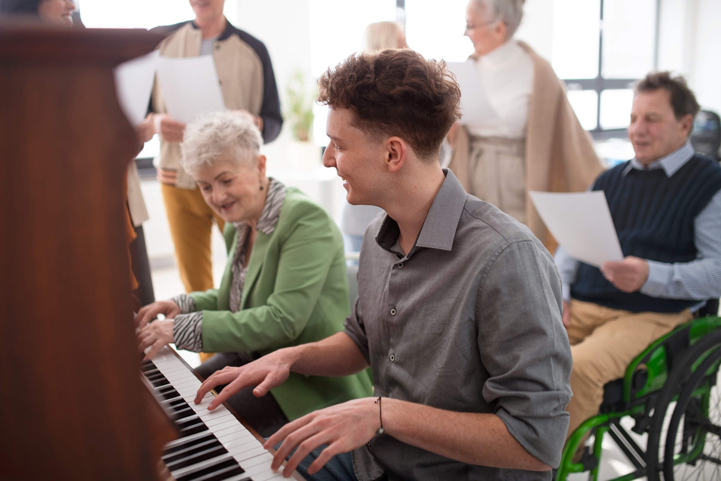 Senior living activity – caregiver and senior playing piano together, fostering connection and joy.