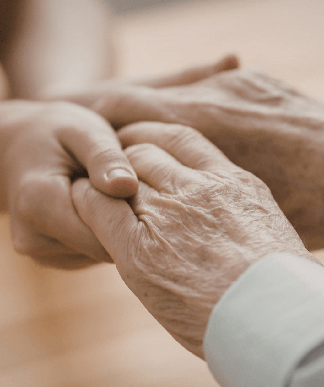 Caregiver holding an elderly person’s hands, showing compassion and supportive senior care