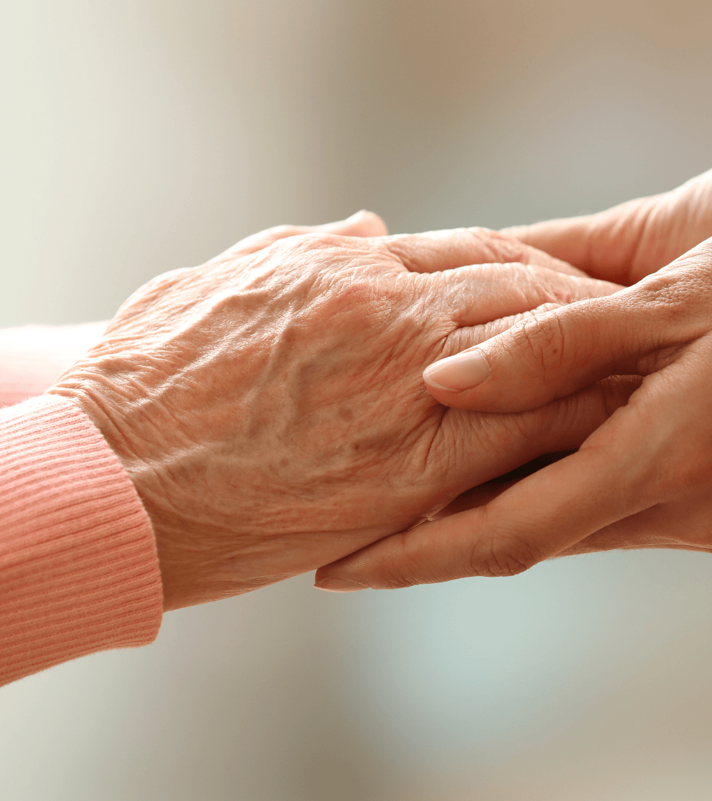 Caregiver holding an elderly person’s hand to provide comfort and support