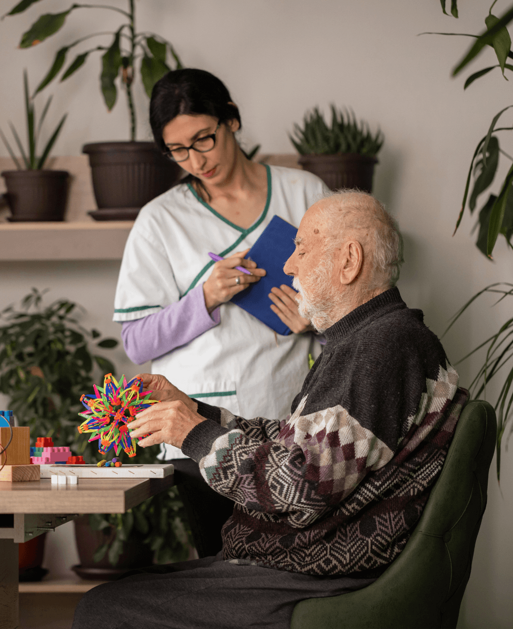 Caregiver supporting an older adult during a cognitive activity in a memory care setting
