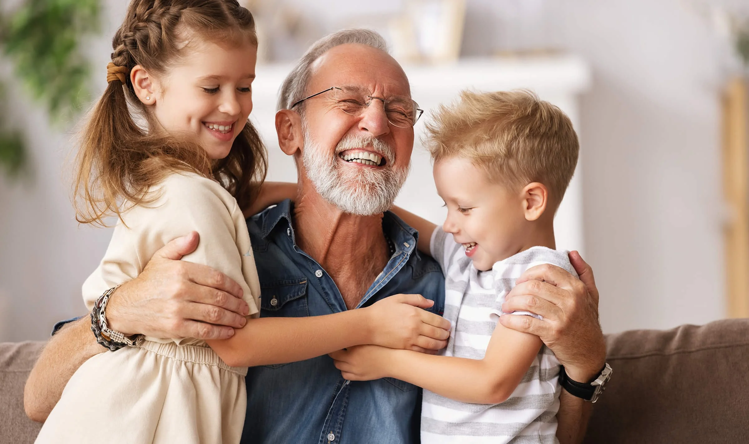 Grandfather laughing and hugging his grandchildren, symbolizing family connection and the joy of quality senior care.