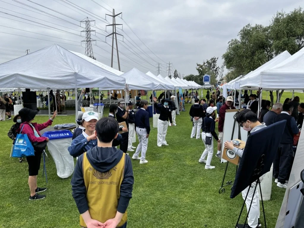 An outdoor community event educating people about electrification, featuring rows of booths