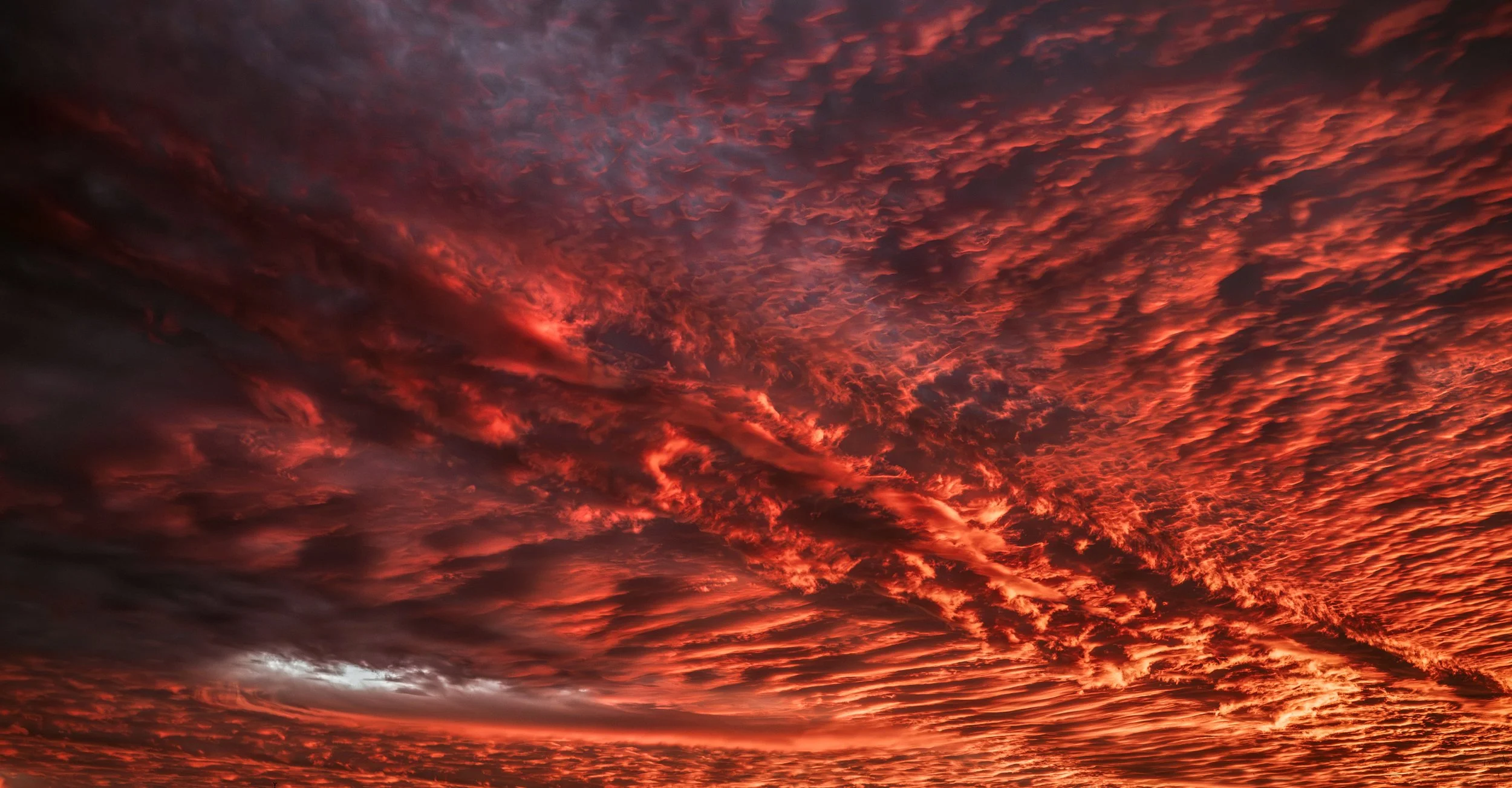 A vibrant sunset sky filled with red, orange, and dark clouds.