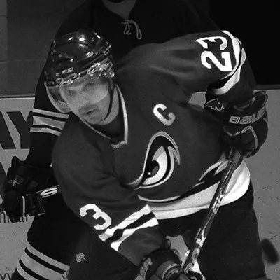 Joel Harris wearing a hockey jersey and helmet playing hockey.