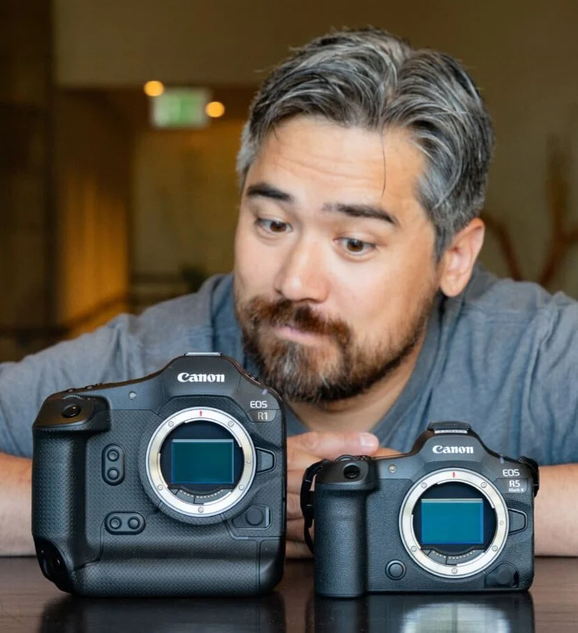 Chris Niccols looking at two Canon cameras placed on a table.