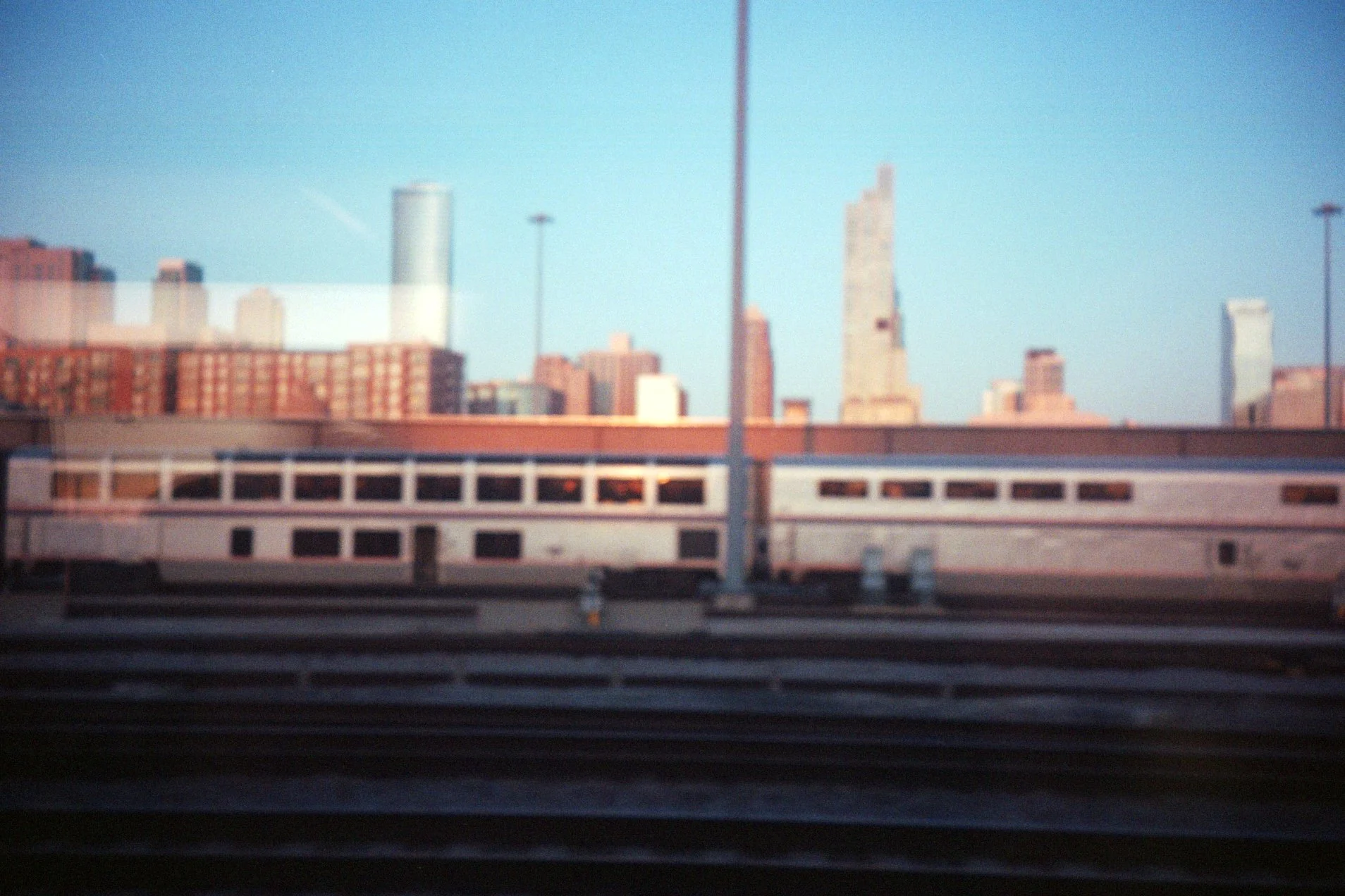 View of a city skyline with tall buildings, seen through a window that reflects the interior ceiling.