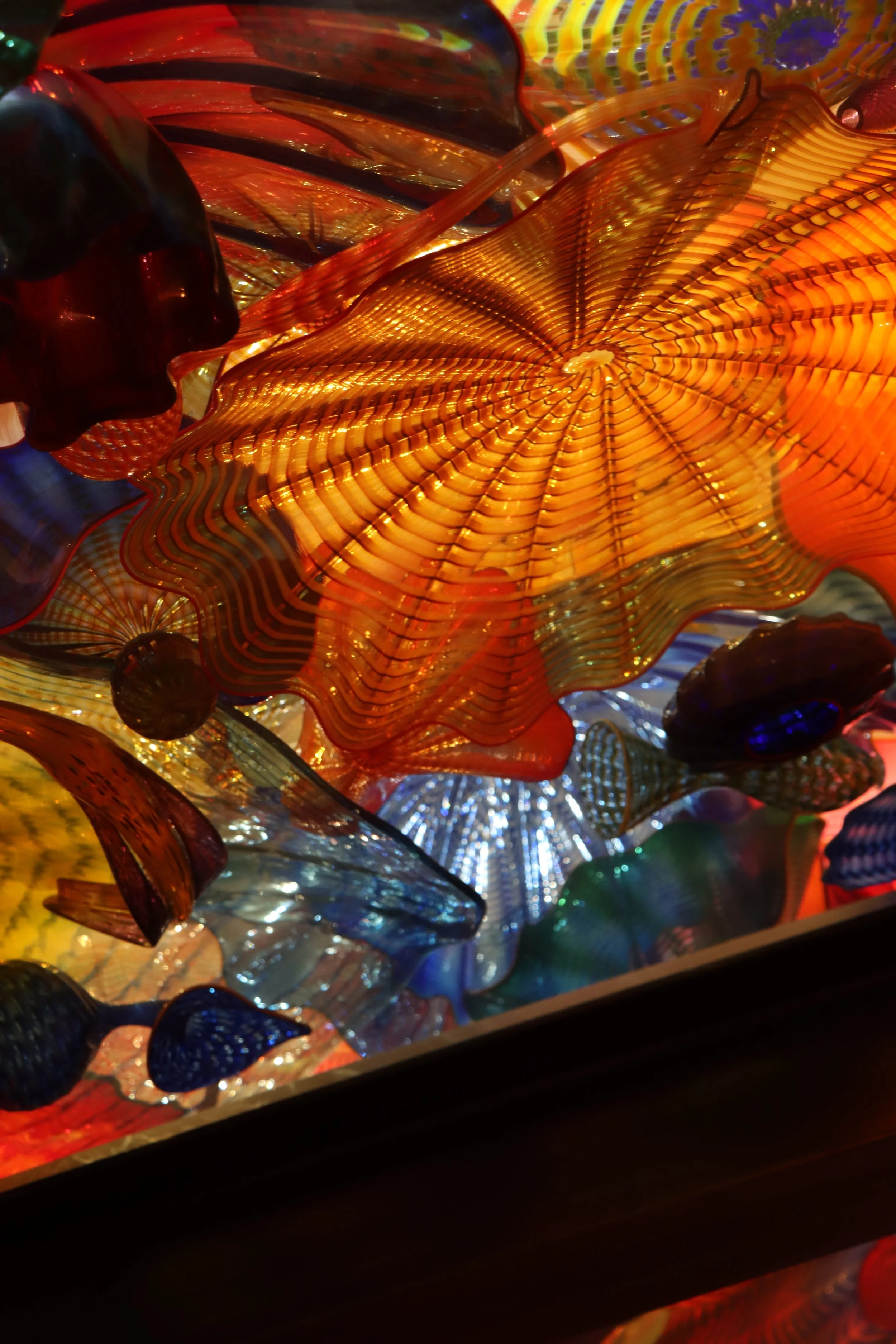 Close-up of colorful, abstract glass art with swirling patterns and vibrant orange, blue, and red hues.