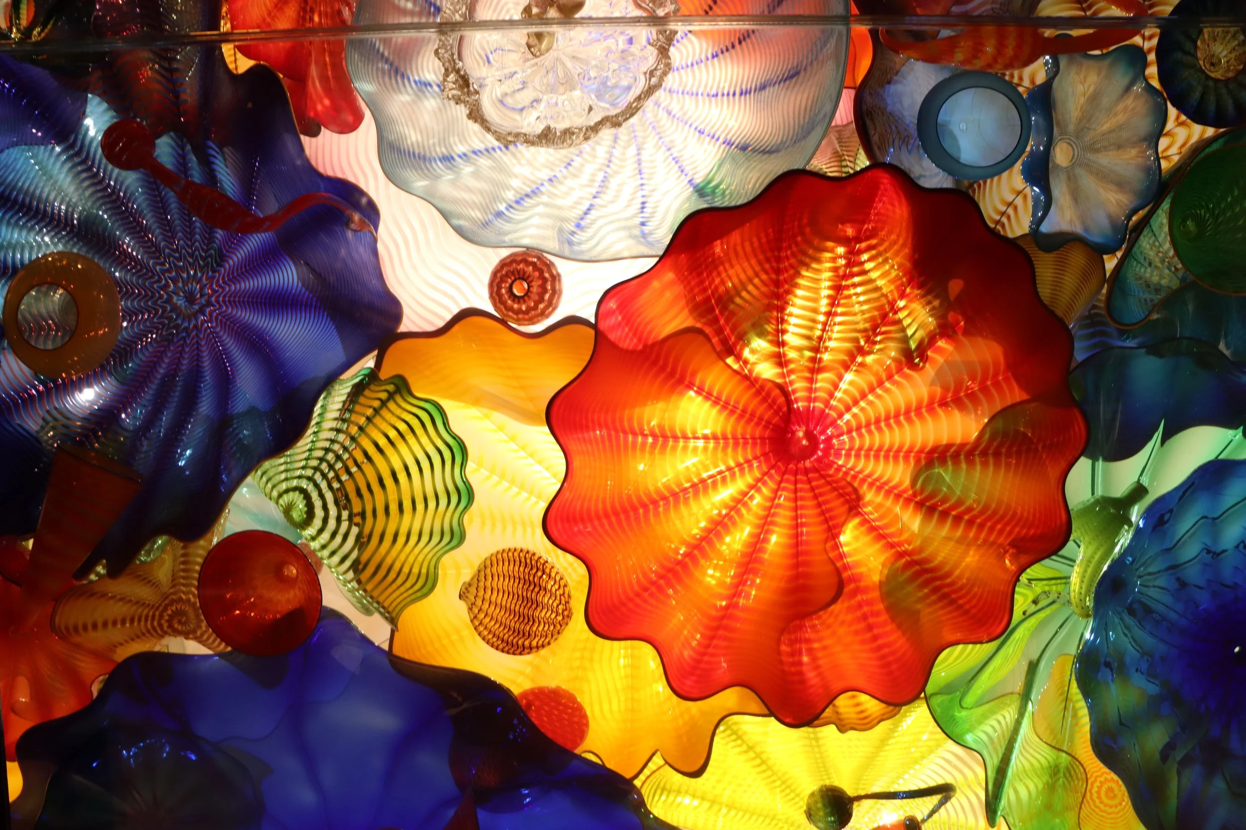 Colorful glass art installation with various shapes and vibrant colors, illuminated from behind.