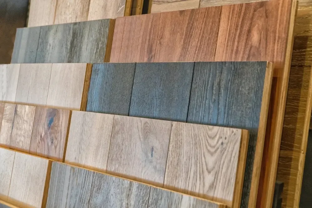 Display of several wooden flooring samples in different colors and finishes arranged on a table in a store.
