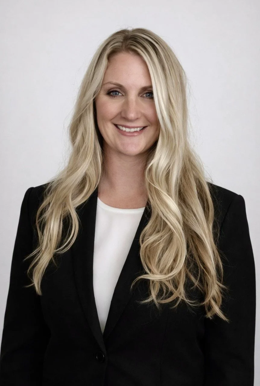 Blonde white woman in her 30s in a black blazer and white top