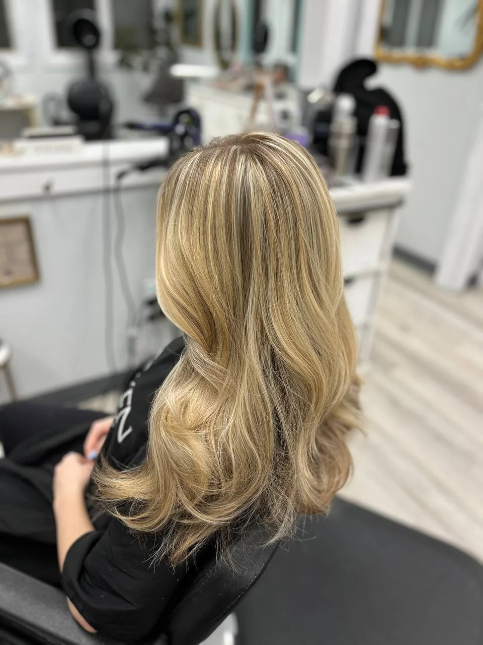 Blonde woman with styled hair sitting in a salon chair.