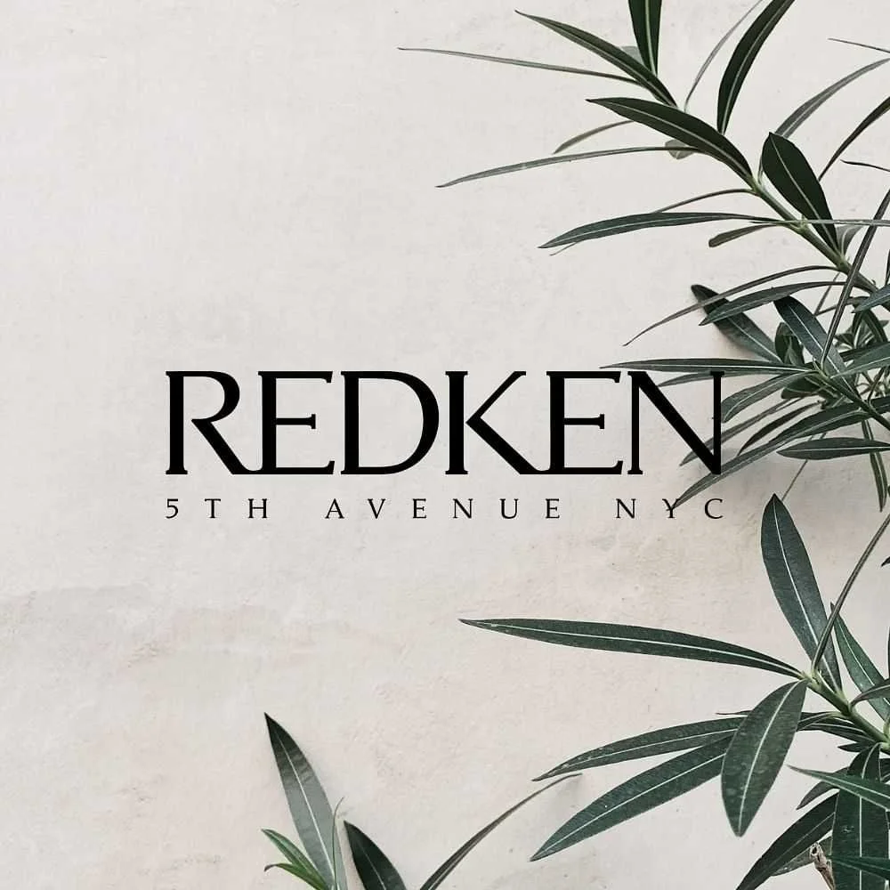 Sign for REDKEN on 5th Avenue in NYC with green foliage around the sign.