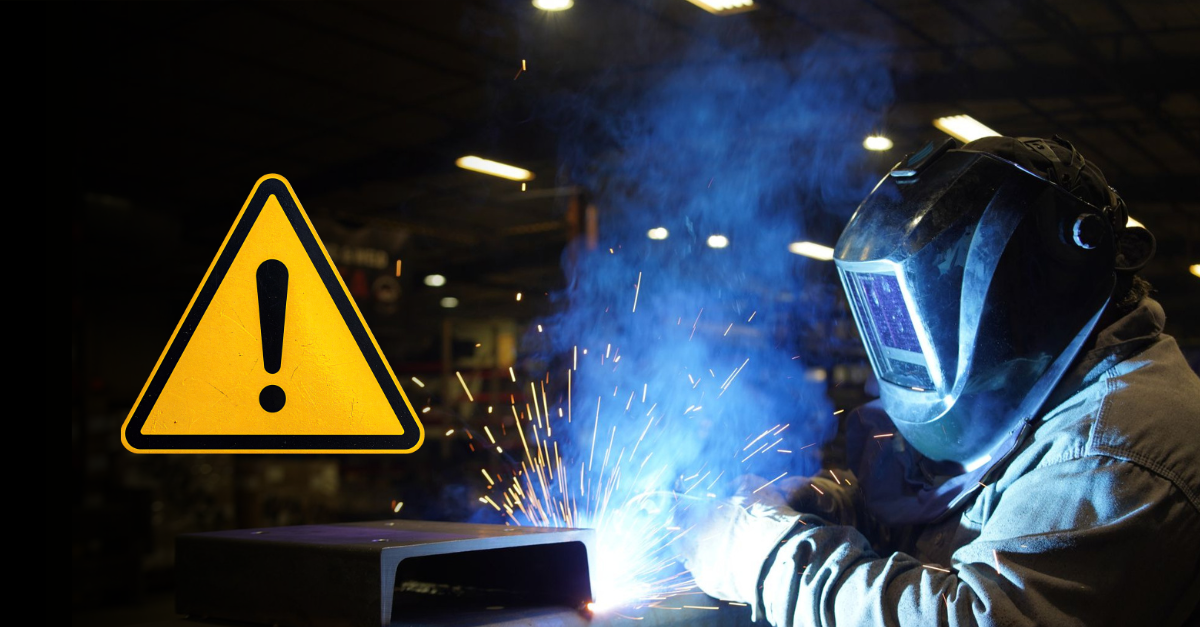 Welder in protective gear actively welding metal in an industrial shop, with sparks flying and blue smoke rising, alongside a yellow caution warning symbol indicating workplace safety awareness.