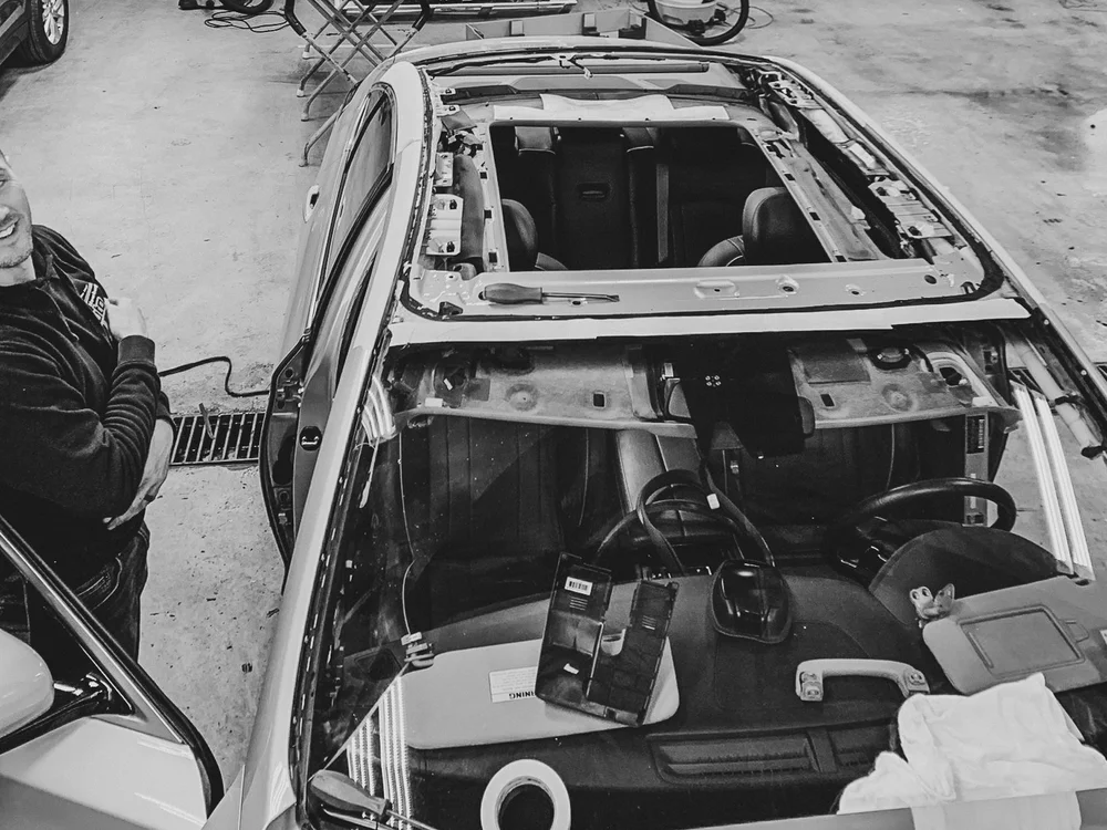 Black and white photo of a car with its interior roof exposed in the garage