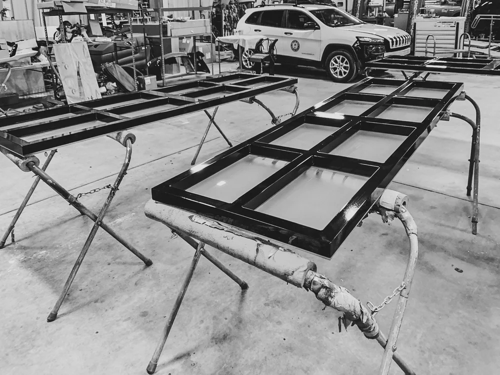 Black and white image of the workshop with a vehicle and workbenches