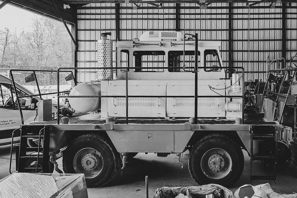 Monochrome image of a military vehicle inside a metal barn