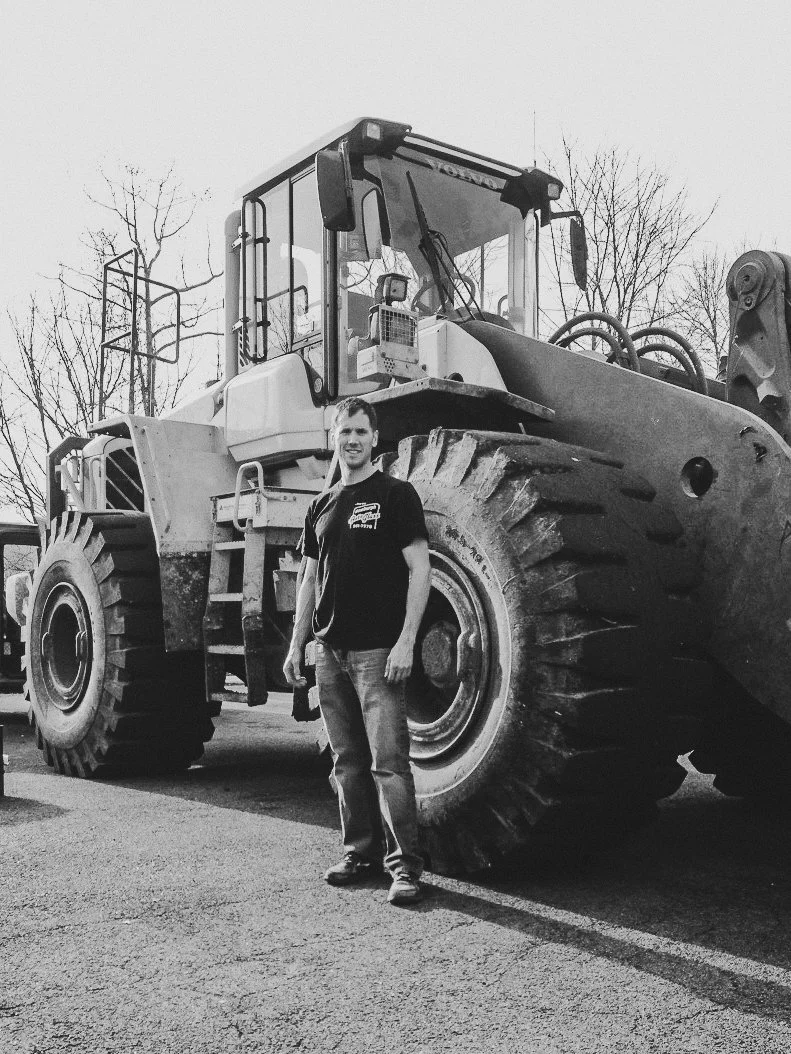 Black and white photo of a man beside a large heavy-duty vehicle