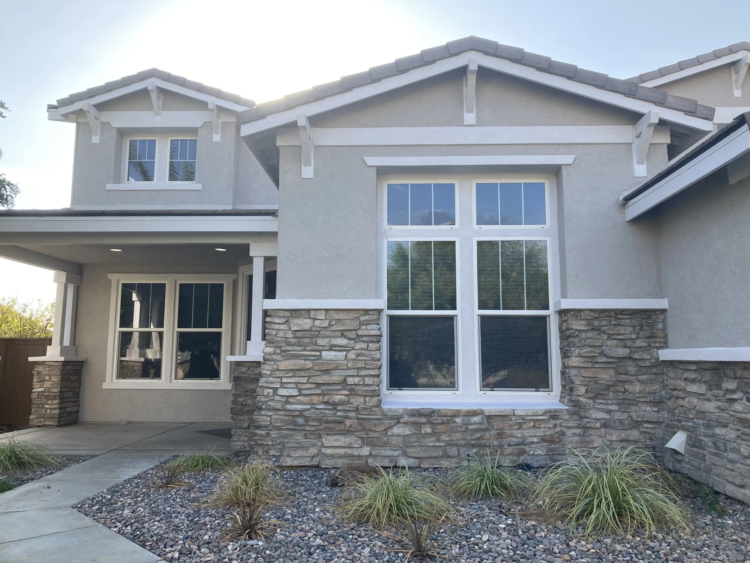 Exterior with classy neutral beige gray color scheme that matches stonework with white trim painted by Garrett Dalton Inc