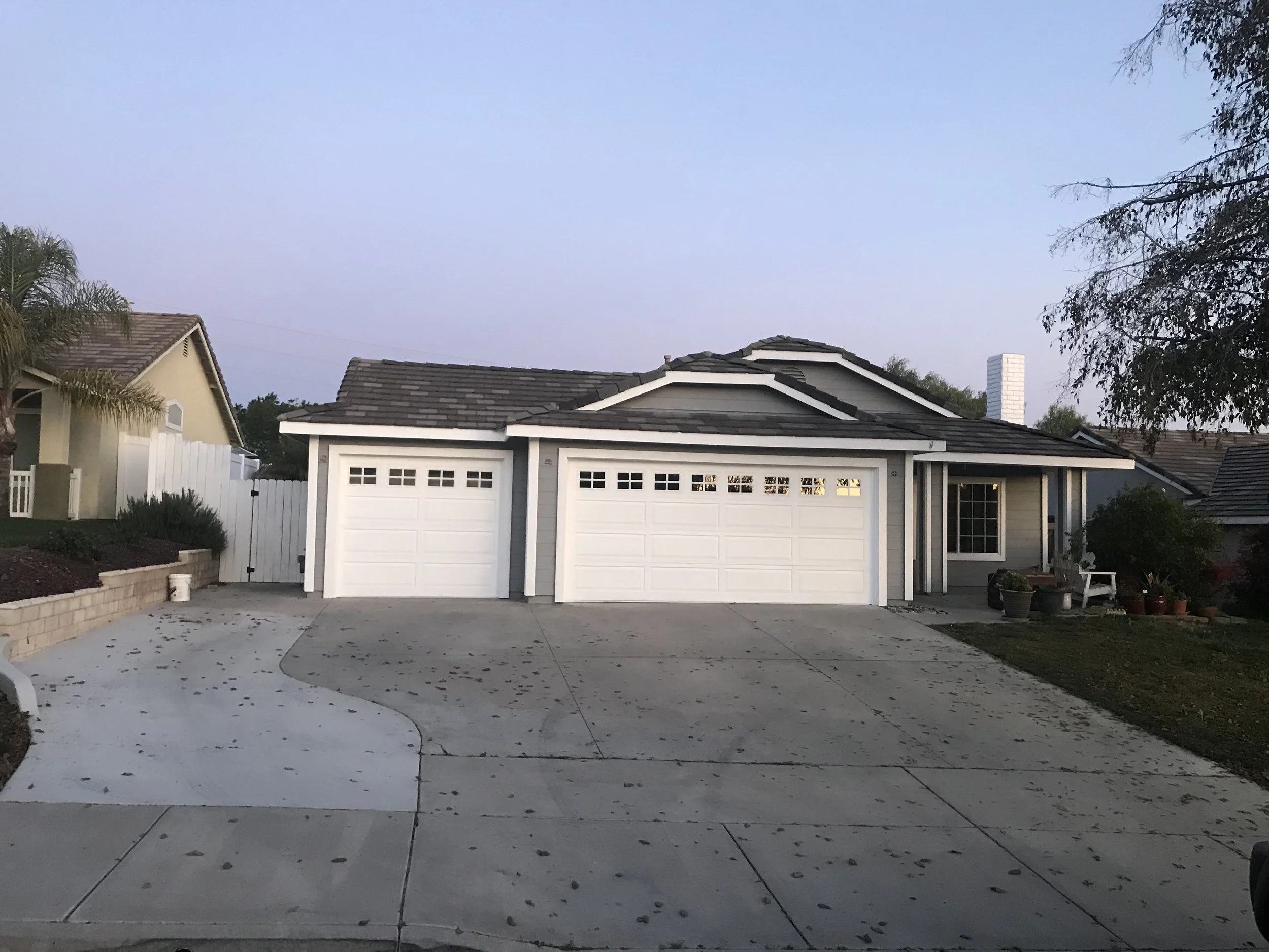 Gray home exterior with white garage doors and trim painted by Garrett Dalton Inc