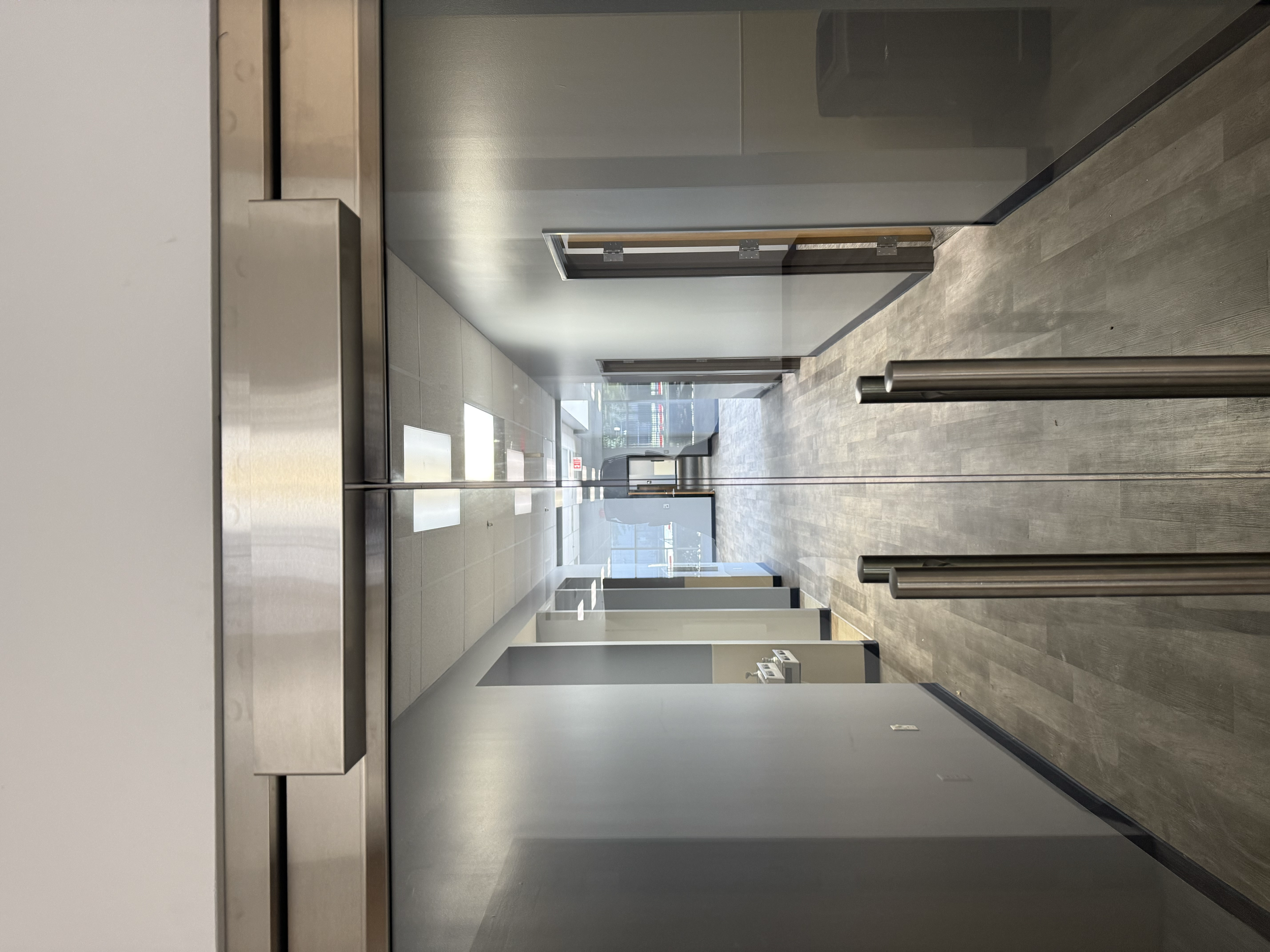 Double Securitron Maglock with custom stainless steel cover and bracket on Herculite door