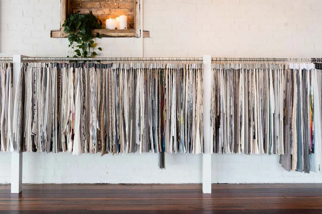 A fabric sample display with numerous fabric swatches hanging on a rack in an interior space.