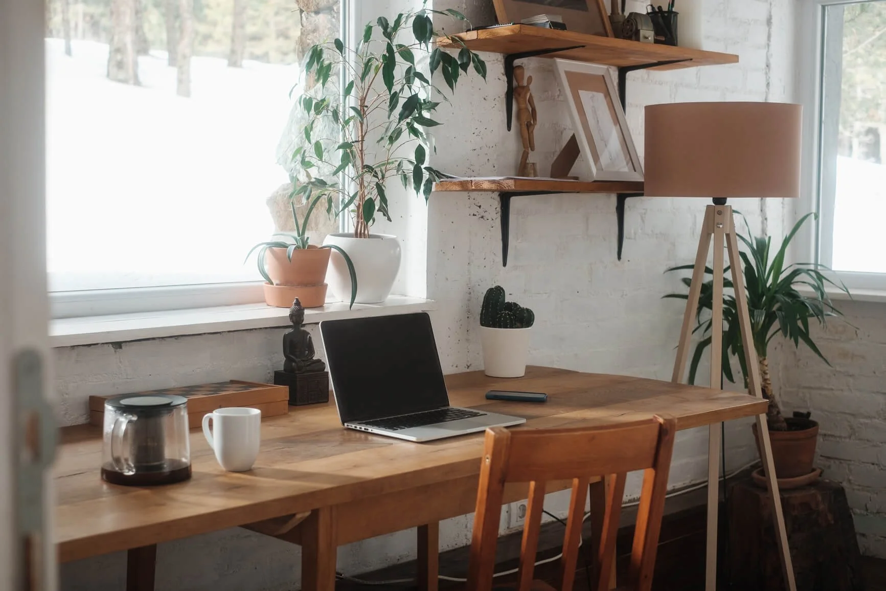 Cosy home office for Reflx Designs Squarespace web designer with white walls, wooden desk with open laptop and plants.