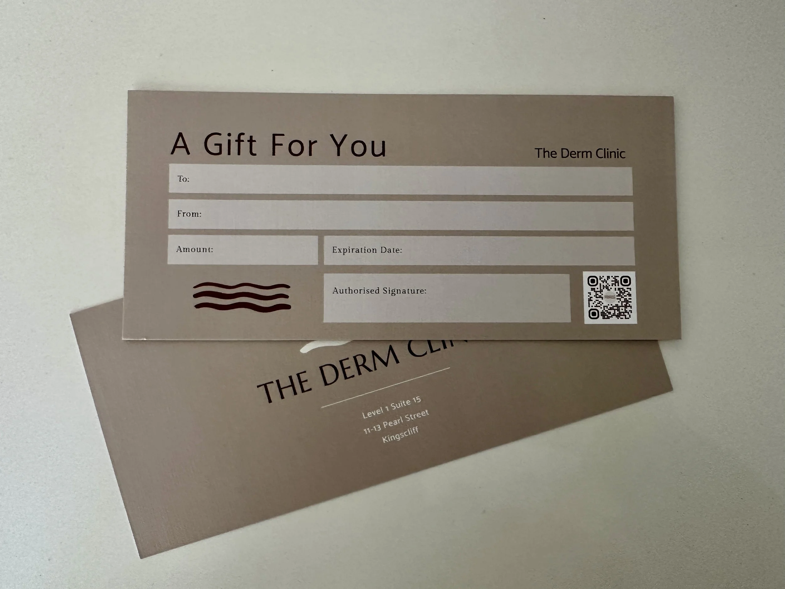 Gift cards for your aesthetic treatments, skin needling, The Derm Clinic Kingscliff, with blank spaces for recipient, sender, amount, expiration date, and authorized signature, featuring two QR codes and a wavy red line.