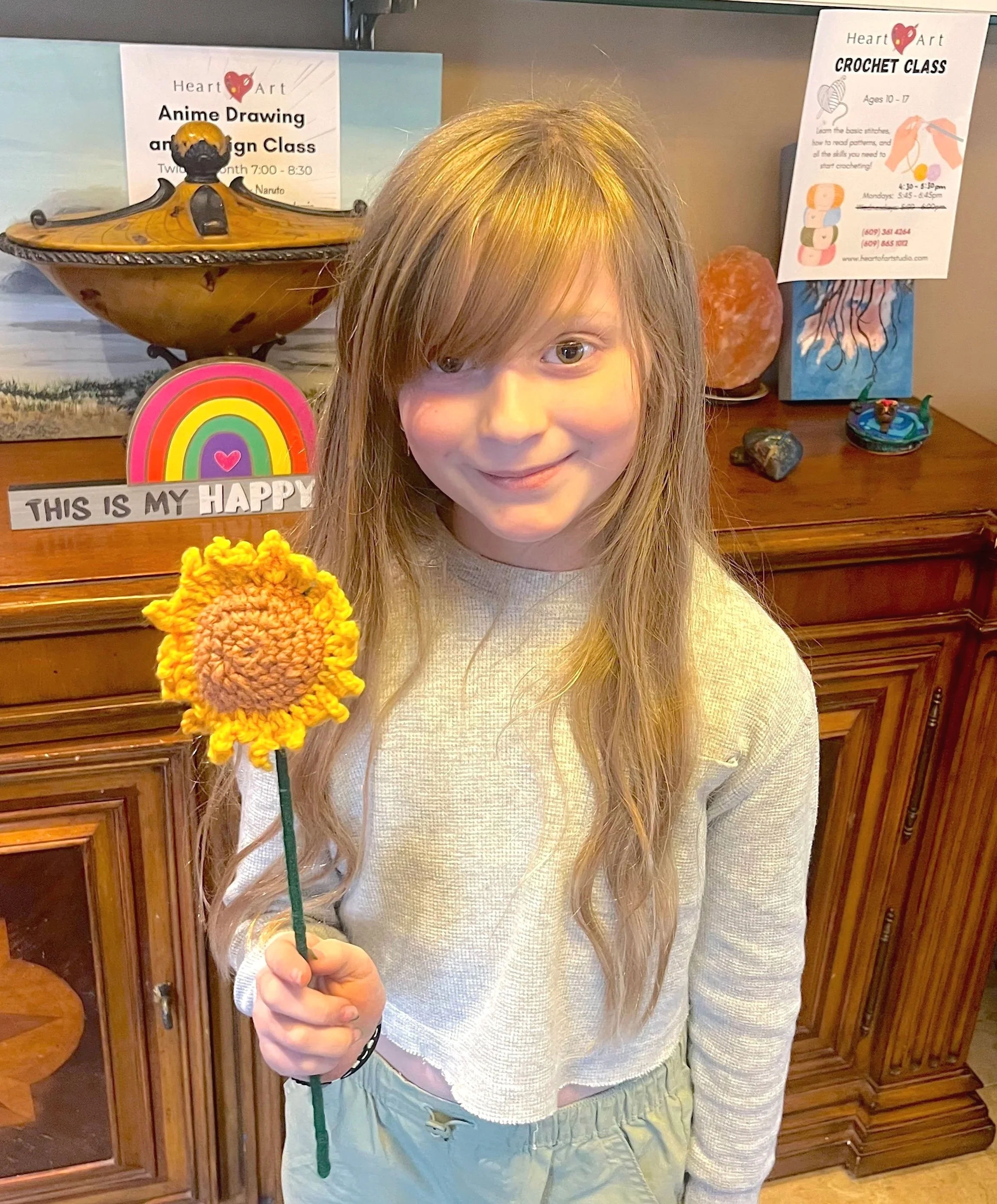 Young crochet student showing a finished crochet sunflower project at Heart of Art Studio art classes