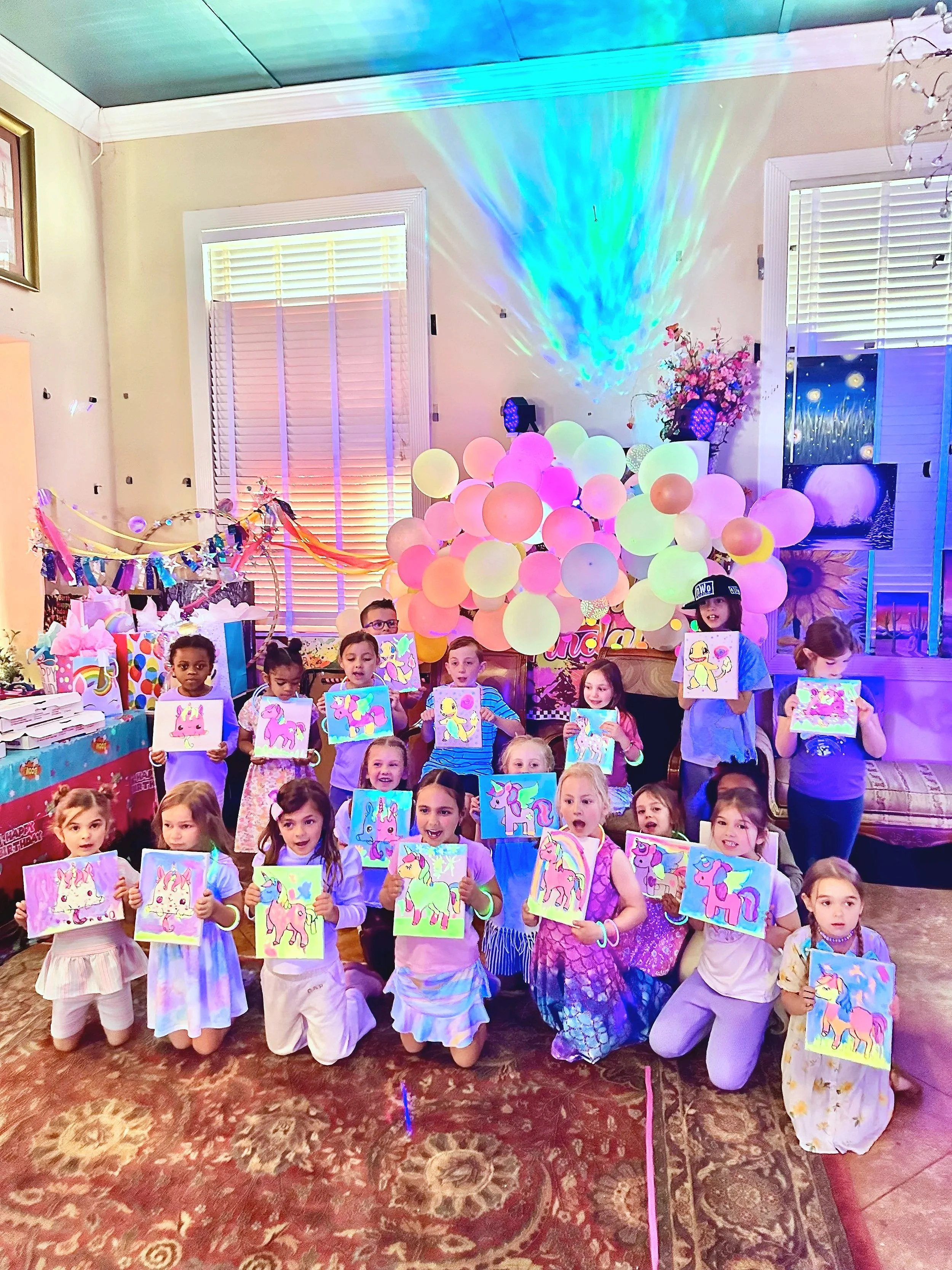 Group picture of kids display after they've finished their paintings in front of balloon arch
