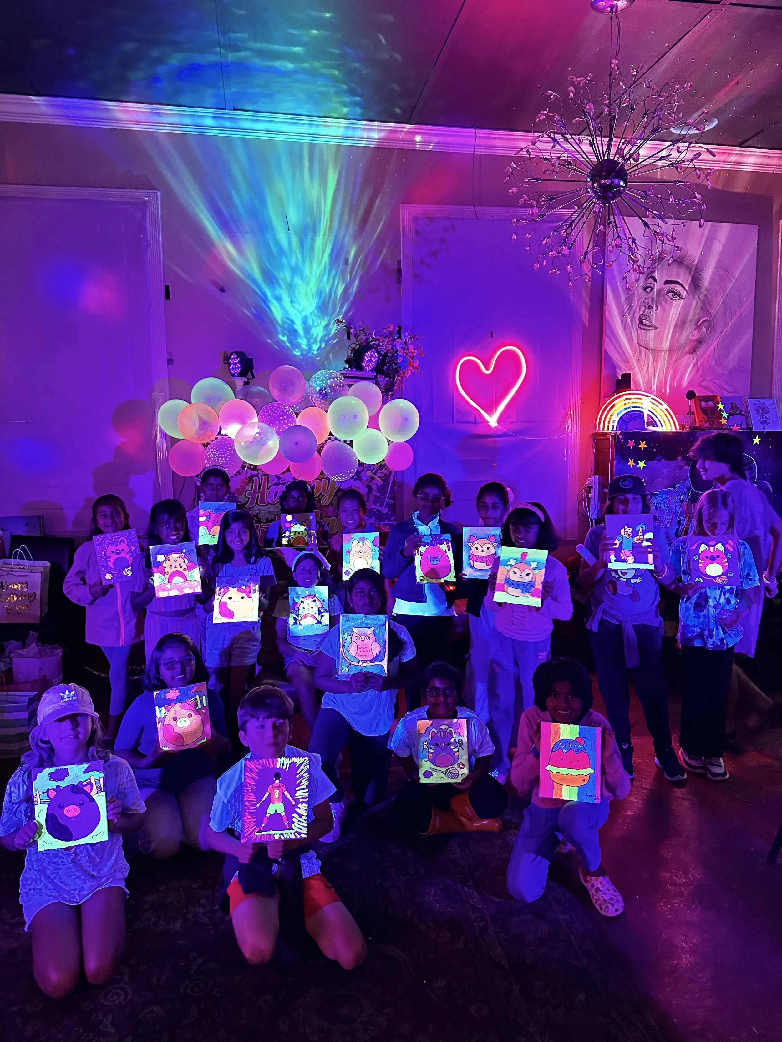 Kids showing their finished glow paintings at the end of a glow art birthday party at the Heart of Art Studio