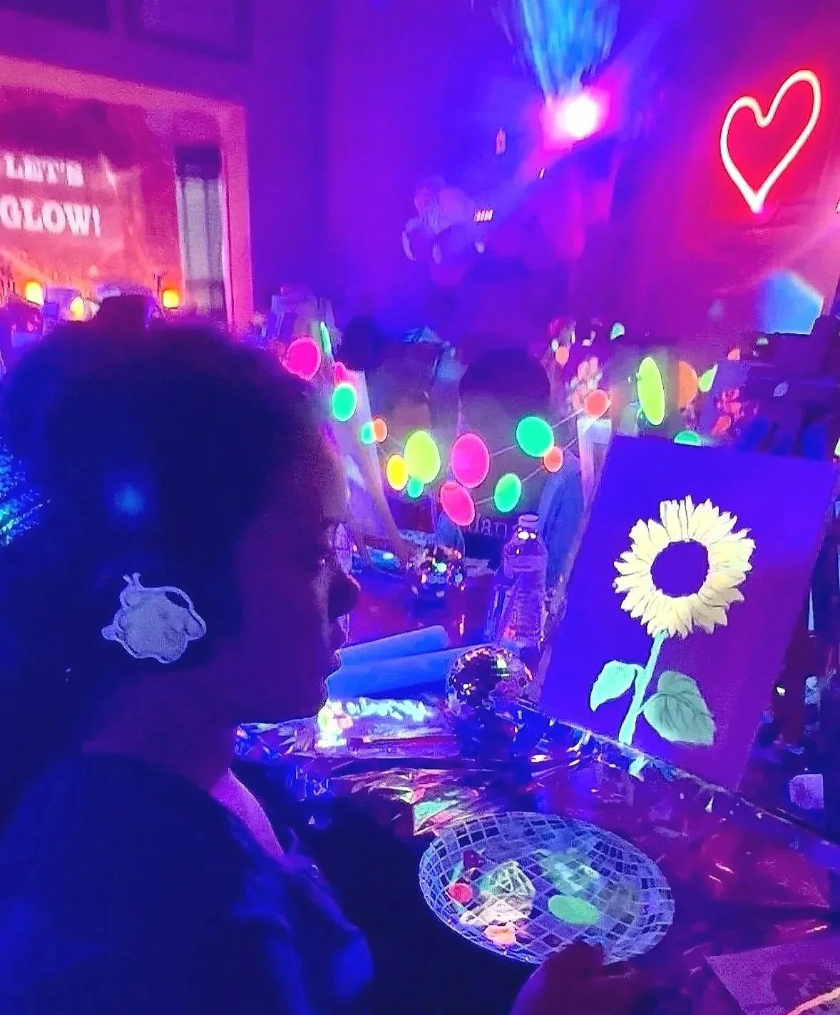 Neon glow painting of a sunflower created by kids during an art birthday paint party