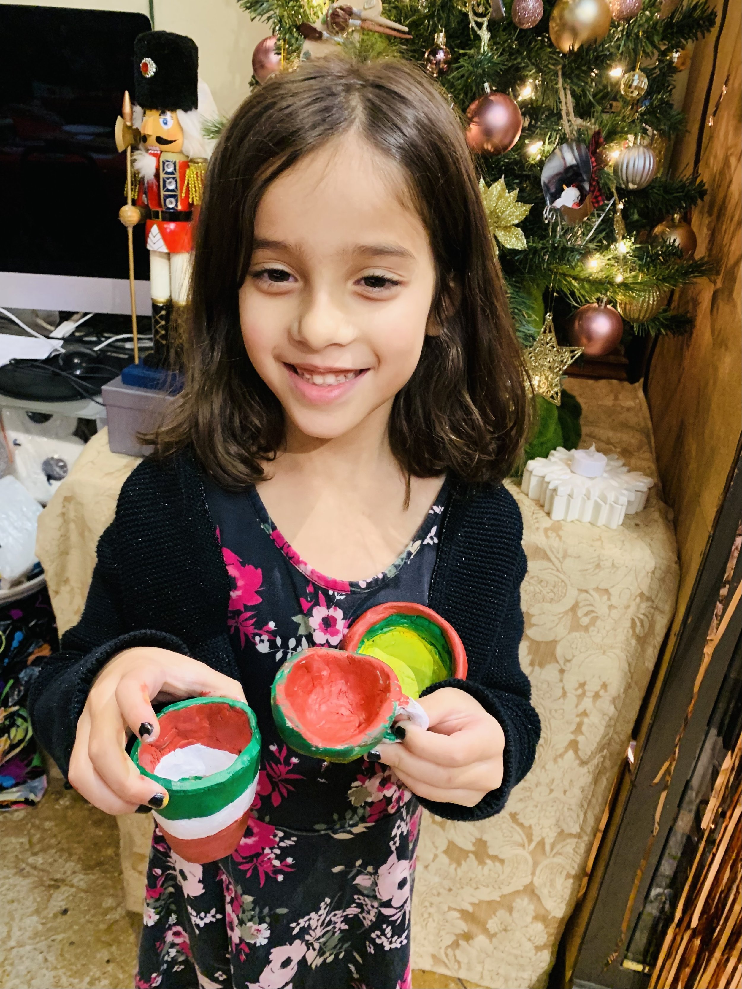 Young student holding handmade clay bowls art pieces created in a kids art class