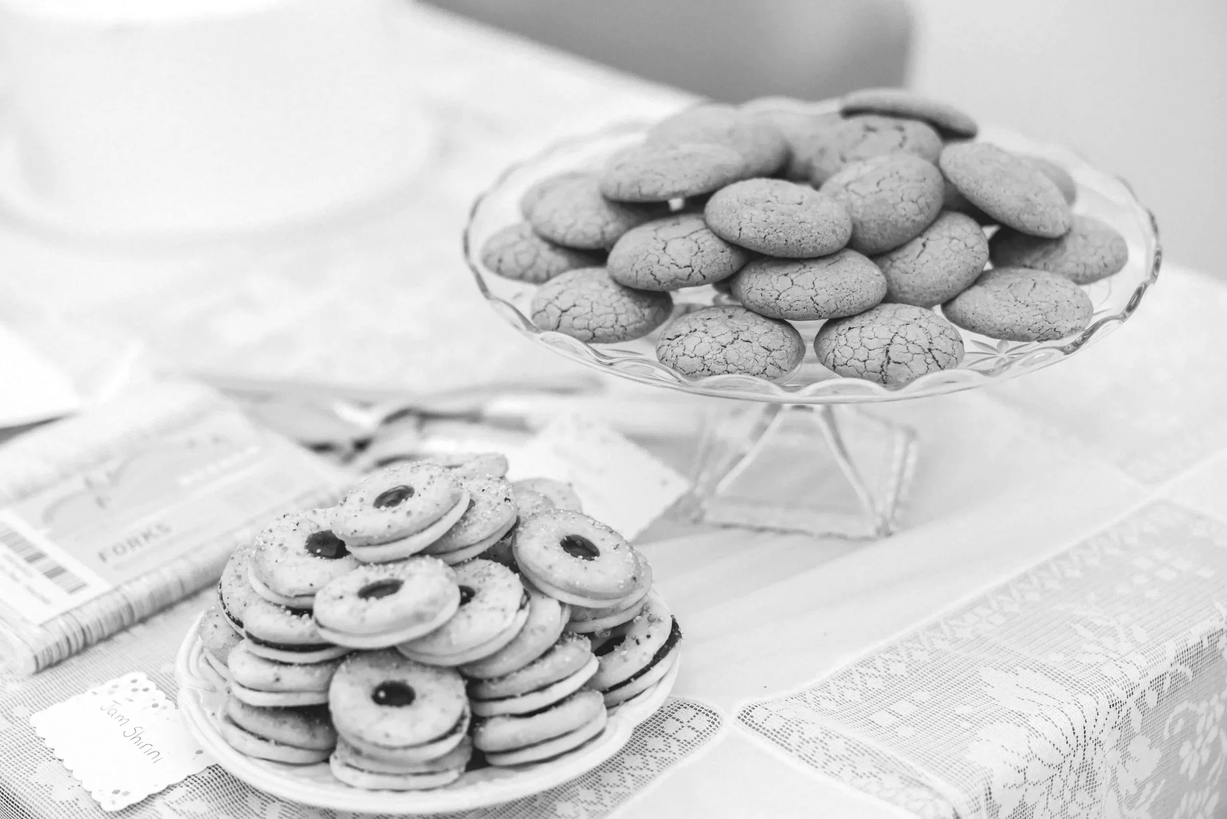 A glass dish filled with cookies on a table, with a plate of cookies nearby, all in black and white in a Bellingham wedding.