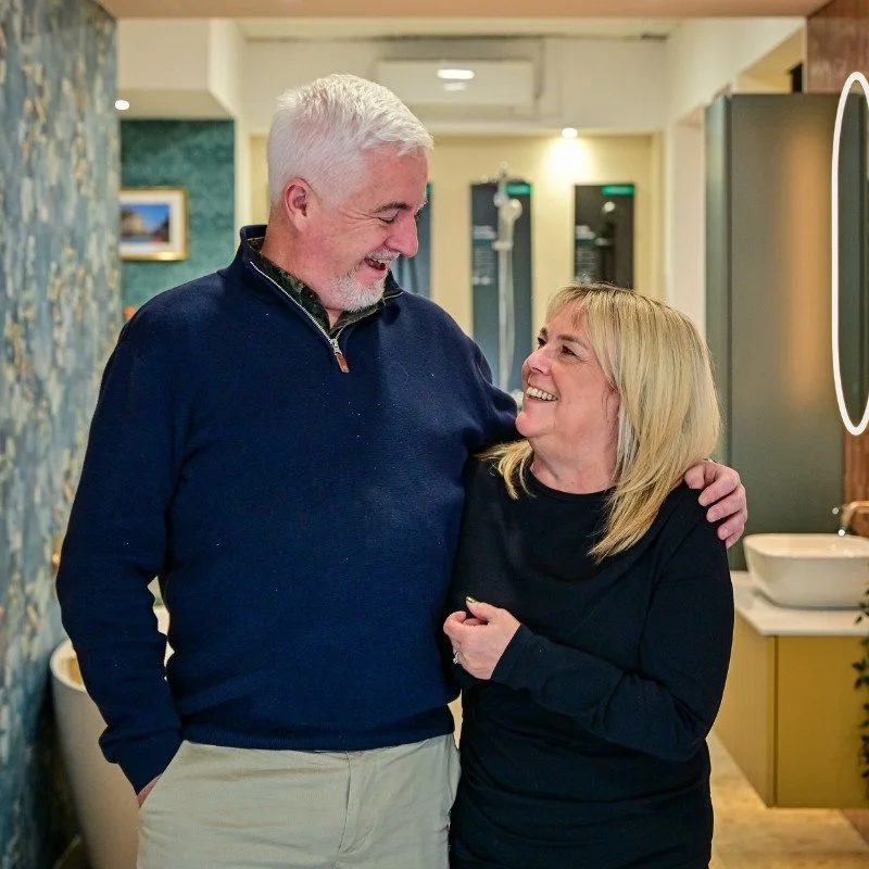 A smiling man and woman sharing a laugh in a warmly lit room.