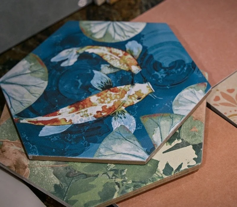 Decorative tiles with aquatic theme, featuring koi fish swimming among lily pads and water ripples, in shades of blue, green, and orange.