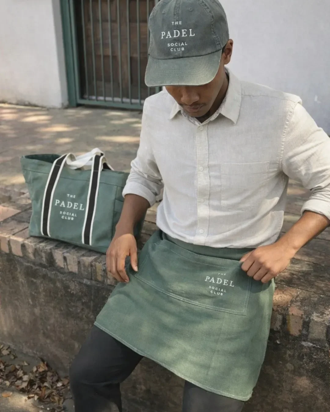Branded olive green canvas tote bag and matching apron for The Padel Social Club, handmade by Soli in Cape Town for sustainable merchandise or corporate gifts.