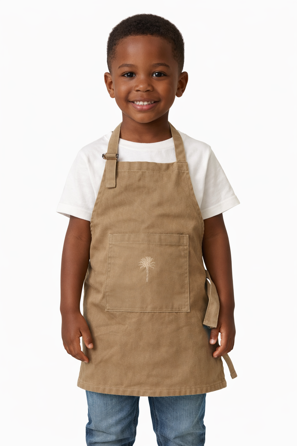 A young boy wearing a canvas kiddies apron with Palm embroidered in cream, handmade by Soli in Cape Town for sustainable hotel guest amenities, made in Cape Town.