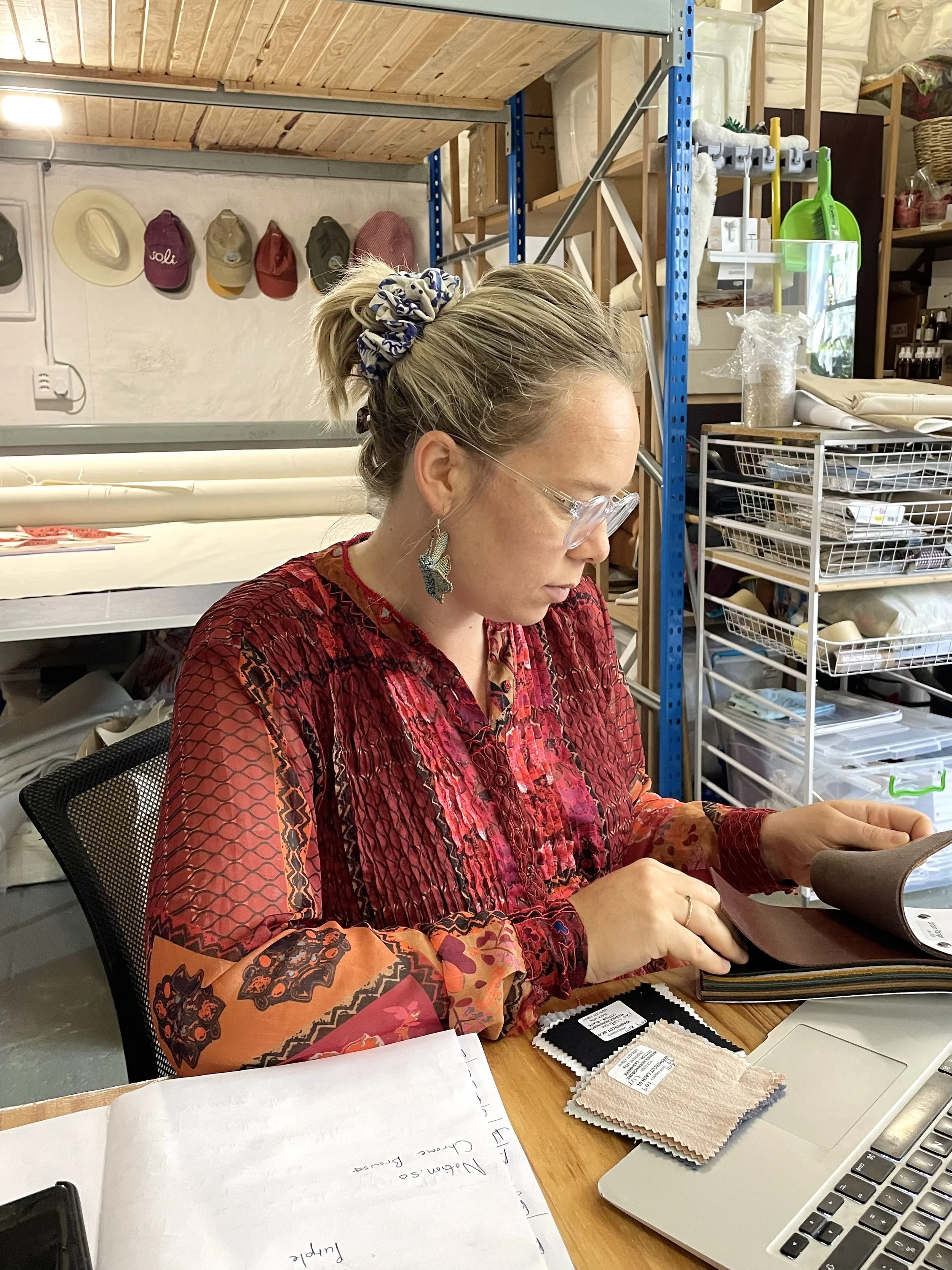 Person reviewing fabric samples at a desk in a workshop.