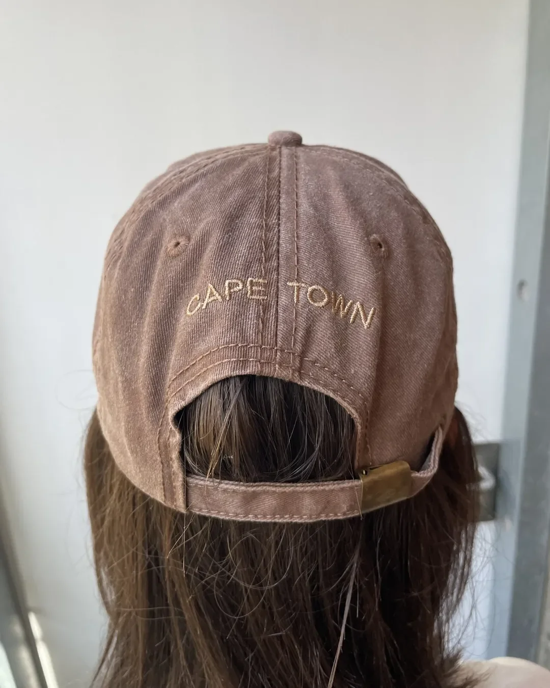 Back view of a cocoa brown vintage washed cotton cap featuring custom "The Strangers Club" and "Cape Town" embroidery, highlighting Soli's high-quality sustainable corporate branding.