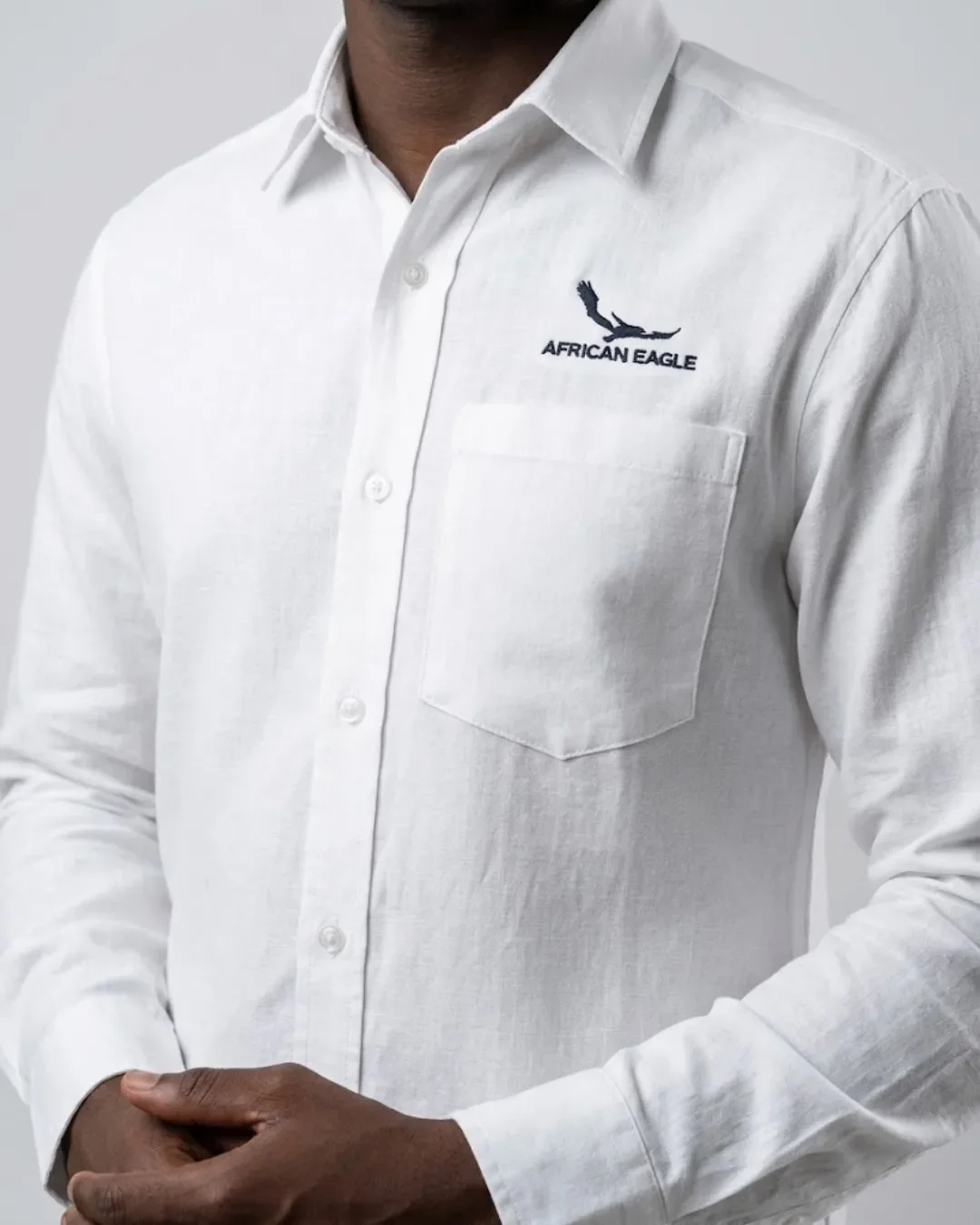 Model wearing a tailored white long-sleeve corporate shirt with subtle chest logo branding, Handmade by Soli in Cape Town for custom staff shirts.