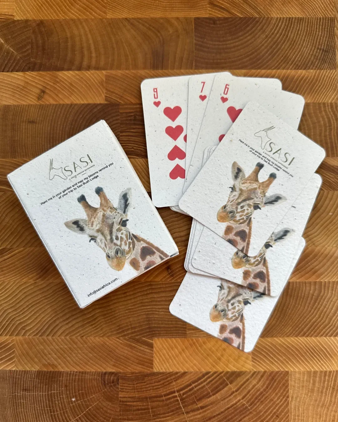 A deck of custom-branded plantable playing cards with a giraffe illustration and heart suits, made from 100% recycled seed paper by Soli in Cape Town as a corporate gift.