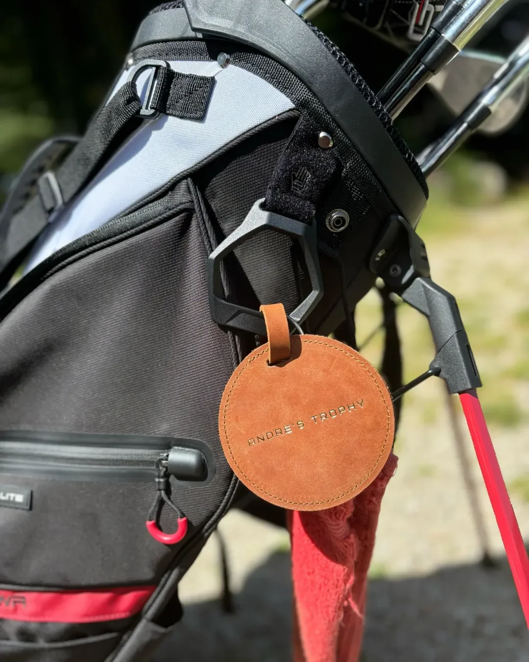 A circular tan leather golf tee holder with three wooden tees inserted and a custom embossed logo, Handmade by Soli in Cape Town for sustainable merchandise or corporate gifts.