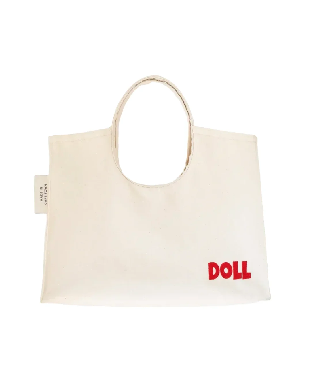 A cream heavy canvas Doll Bag featuring a rounded cotton handle and a bold red embroidered "DOLL" logo in the bottom corner, handmade by Soli in Cape Town for sustainable merchandise or corporate gifts.