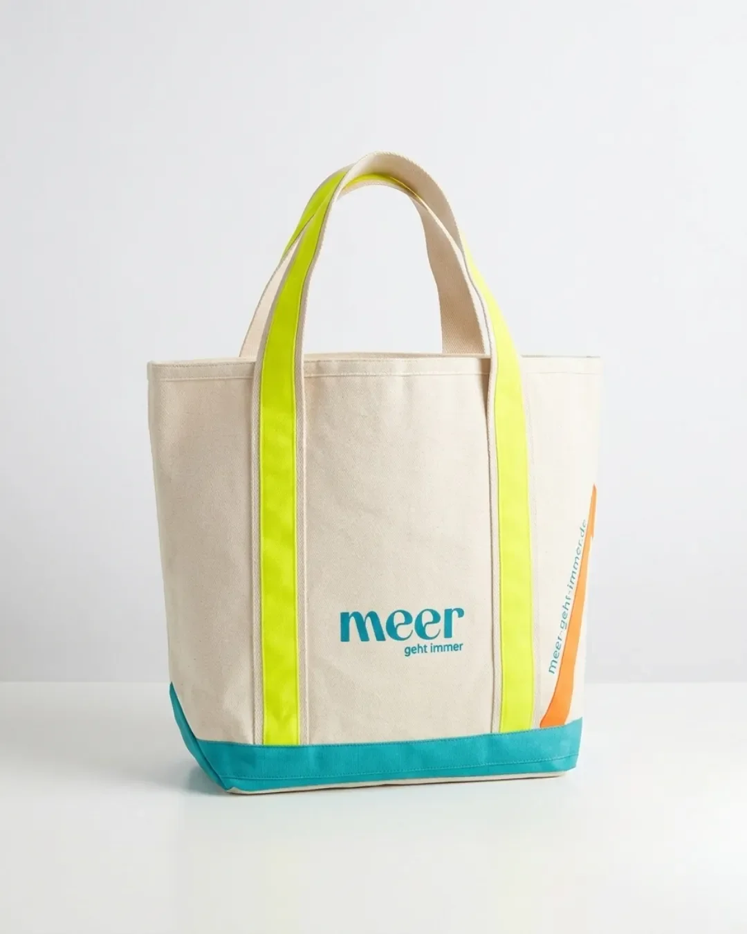 Premium cream oxford canvas tote bag featuring vibrant neon yellow straps, a teal base panel, and a custom blue "meer geht immer" printed logo, ideal for high-quality corporate gifting.